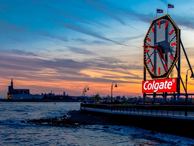 หอนาฬิกา Colgate ริมฝั่งแม่น้ำในช่วงพระอาทิตย์ตกดิน พร้อมท้องฟ้าสีส้มและวิวเมืองที่สวยงาม
